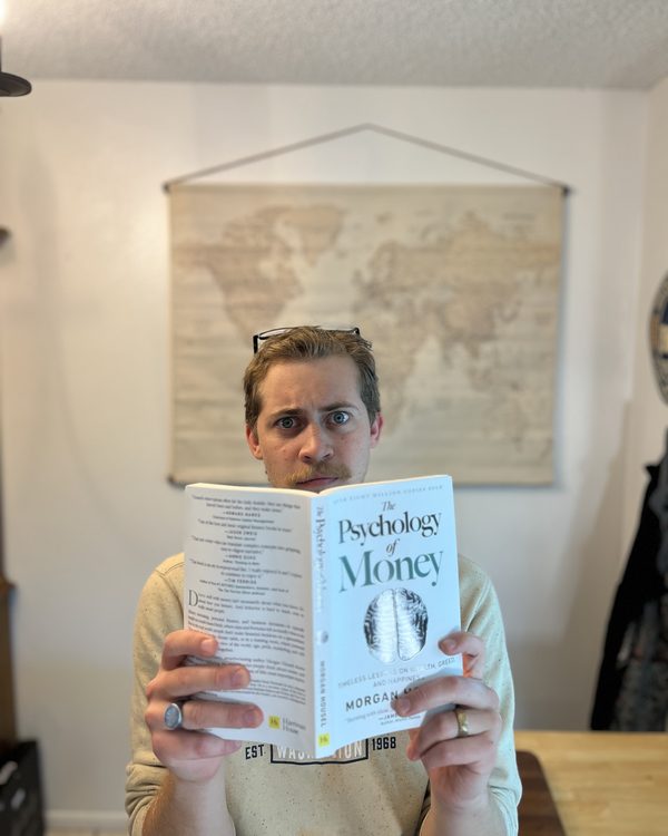Josh peering over a copy of The Psychology of Money